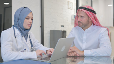 Doctor in Hijab Typing Treatment Plan while Talking with Patientの写真素材