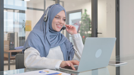 Woman in Hijab with Headset Talking Online in Call Centerの写真素材