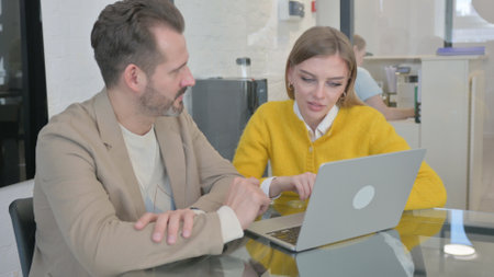 Young People Discussing Work on Laptopの写真素材