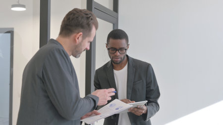 African Entrepreneur Discussing Work with Employee, Standing in Officeの写真素材