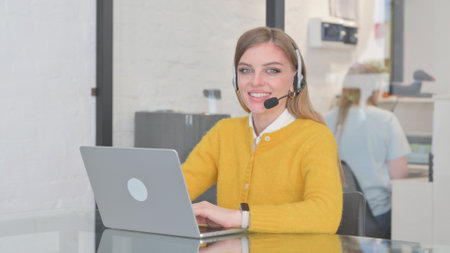 Smiling Woman with Headset in Call Center Looking at Cameraの写真素材