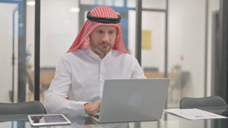 Arab Man Working on Laptop in Officeの写真素材