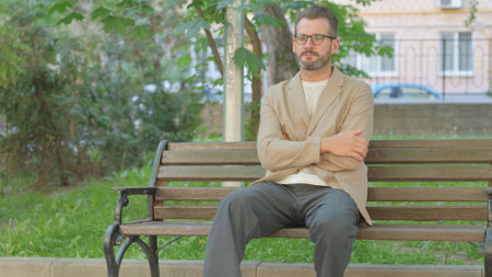 Pensive Young Man Sitting Outdoor on Benchの写真素材