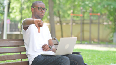 Thumbs Down by Young African Man Using Laptop Outdoor