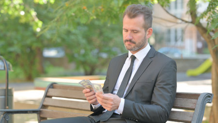 Portrait of Happy Young Businessman Counting Money Outdoorの写真素材