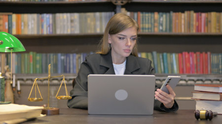 Female Lawyer Using Phone with Laptopの写真素材