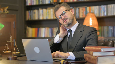 Middle Aged Lawyer having Neck Pain with Laptopの写真素材