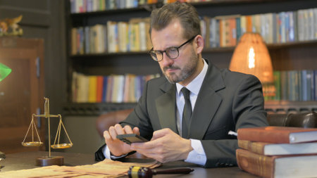 Middle Aged Lawyer Using Smartphone in Officeの写真素材