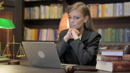 Pensive Female Lawyer Reading on Laptopの写真素材