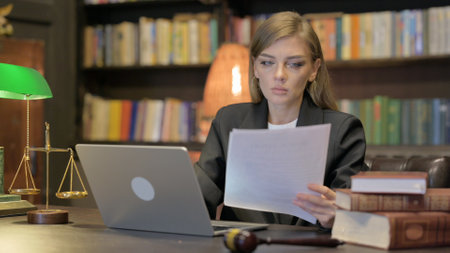 Female Lawyer Doing Paperwork on Laptop in Officeの写真素材