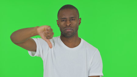 Portrait of African Man with Thumbs Down on Green Backgroundの写真素材