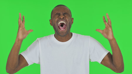 Portrait of Man Screaming Loud on Green Backgroundの写真素材