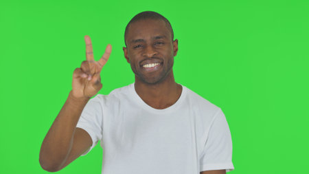 Portrait of African Man with Victory Sign on Green Backgroundの写真素材