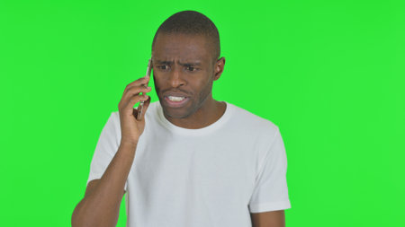 Portrait of Angry Man Talking on Phone on Green Backgroundの写真素材