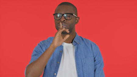 Casual African Man with Silence Gesture on Red Background, Portraitの写真素材