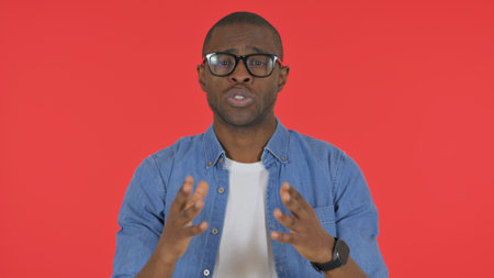 Talking Casual African Man Doing Video Chat on Red Background, Portraitの写真素材