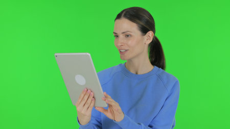 Woman Doing Video Chat on Tablet on Green Backgroundの写真素材