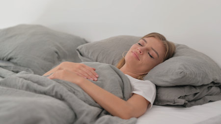 Tired Young Woman Sleeping in Bedの写真素材
