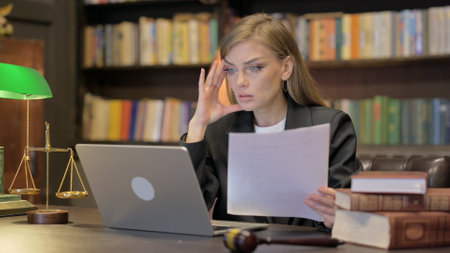 Female Lawyer Having Problem with Paperwork on Laptop in Officeの写真素材