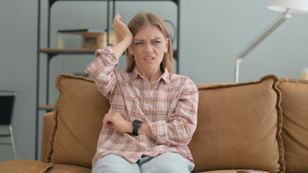 Young Woman with Headache Sitting on Sofa at Homeの写真素材