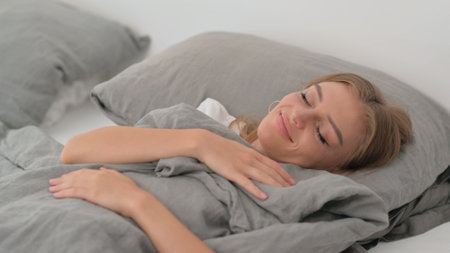 Tired Young Woman Lying Down in Bed to Take Restの写真素材