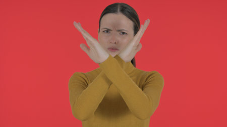 Casual Young Woman Shaking Head in Acceptance on Red Background, Portraitの写真素材