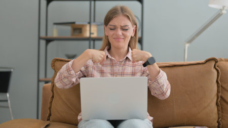 Tired Young Woman with Wrist Pain Using Laptop at Homeの写真素材