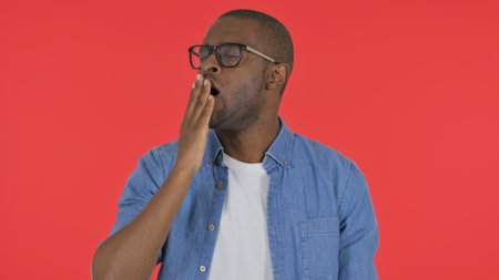 Yawning Casual African Man on Red Background, Portraitの写真素材