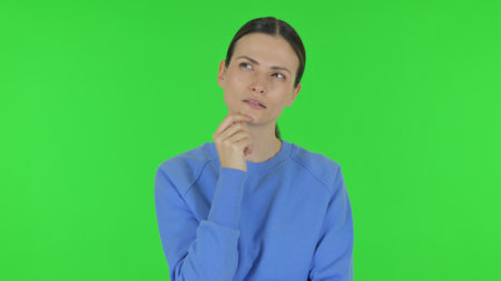 Pensive Woman Thinking an Idea on Green Backgroundの写真素材