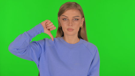 Woman with Thumbs Down on Green Backgroundの写真素材