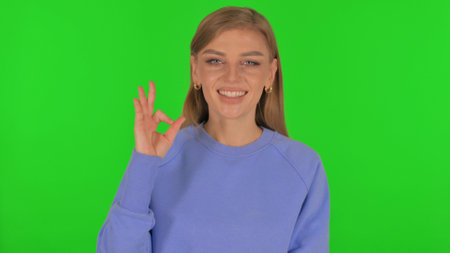 Woman with Okay Sign on Green Backgroundの写真素材