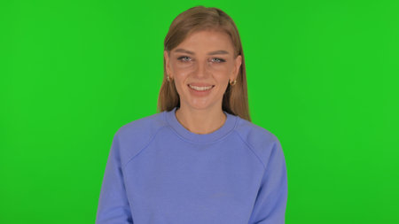 Woman Shaking Head in Acceptance on Green Backgroundの写真素材