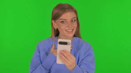 Woman Doing Video Chat via Phone on Green Backgroundの写真素材