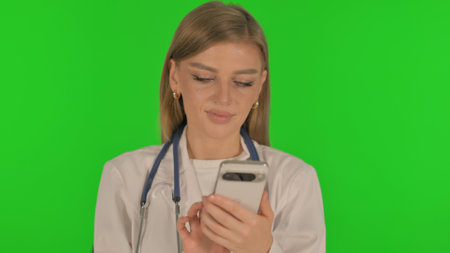 Portrait of Female Doctor Browsing phone on Green Backgroundの写真素材