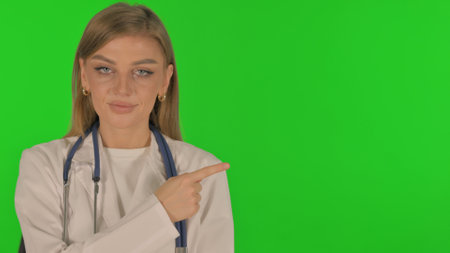 Portrait of Pointing Woman Showing Copyspace on Green Backgroundの写真素材