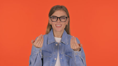 Casual Young Woman inviting People on Orange Background, Portraitの写真素材
