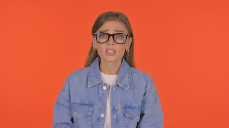 Angry Casual Young Woman Talking in Anger on Orange Background, Portraitの写真素材