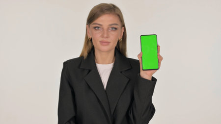 Casual Young Woman Showing Smartphone with Green Screen on Red Backgroundの写真素材