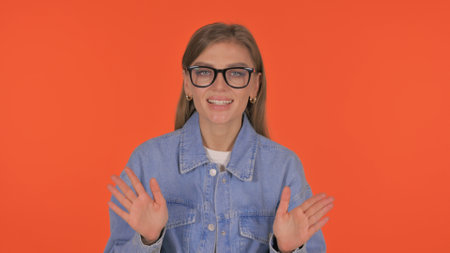 Talking Casual Young Woman Doing Video Chat on Orange Background, Portraitの写真素材