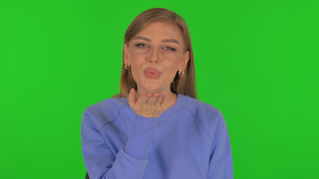 Woman Blowing Flying Kiss on Green Backgroundの写真素材