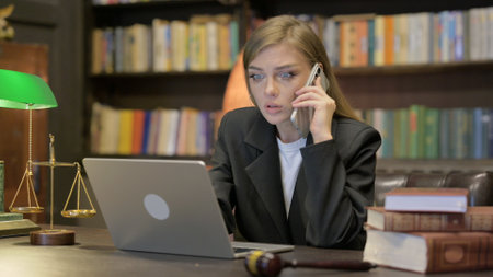 Angry Female Lawyer Talking on Phone while using Laptopの写真素材