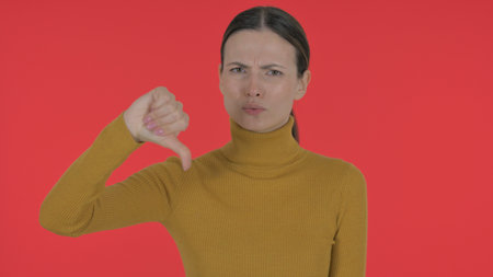 Casual Young Woman with Thumbs Down on Red Background, Portrait