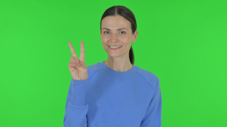 Woman with Victory Sign on Green Backgroundの写真素材