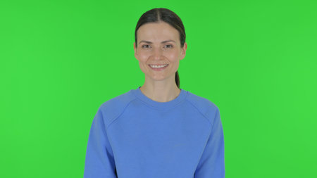 Woman Shaking Head in Acceptance on Green Backgroundの写真素材