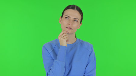Pensive Woman Thinking an Idea on Green Backgroundの写真素材