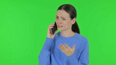 Angry Woman Talking on Phone on Green Backgroundの写真素材