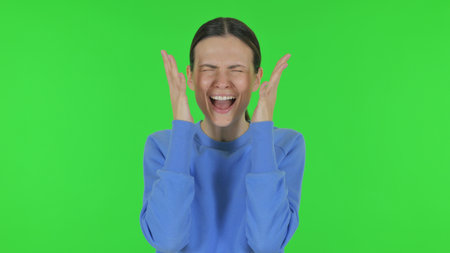 Frustrated Woman Screaming Loud on Green Backgroundの写真素材
