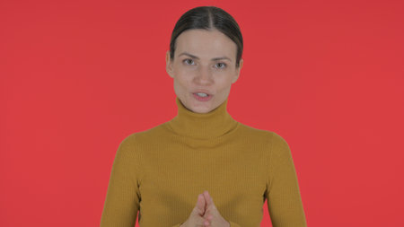Talking Casual Young Woman Doing Video Chat on Red Background, Portraitの写真素材
