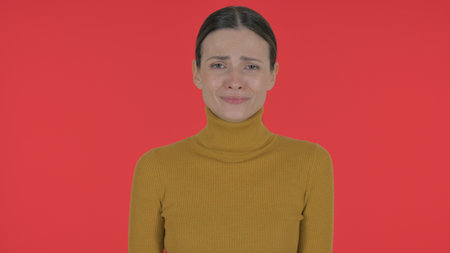Crying Casual Young Woman Feeling Sad on Red Background, Portraitの写真素材