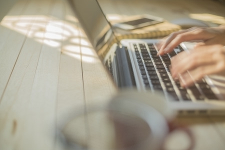 Hand woman typing on laptop on wooden desk